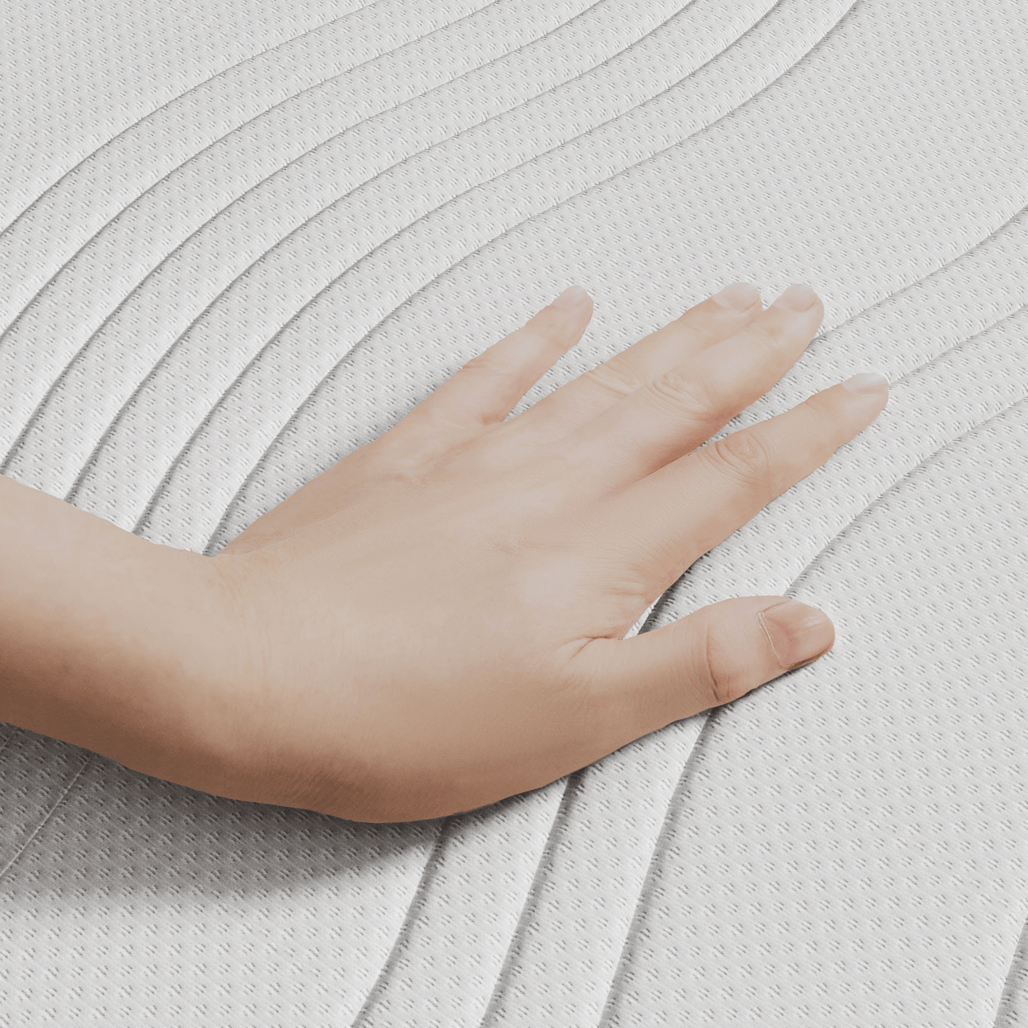Een hand drukt op het witte gestructureerde oppervlak van het Topdekmatras - Hybrid Koudschuim Cool Fresh Tijk met gebogen, verhoogde lijnen, waardoor het drukverlagende comfort wordt benadrukt.
