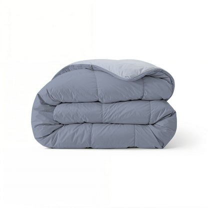 Het Zelesta Comfort Duo Dekbed in ijsblauw & zachtblauw, met een doorgestikt dessin geïnspireerd op klassieke dekbedden, is netjes opgevouwen en perfect als laagje voor het hele seizoen, afgebeeld tegen een effen witte achtergrond.