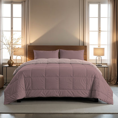 Een netjes opgemaakt bed met de Zelesta Comfort Duo Kussensloop in oudroze, met bijpassende 60x70cm kussens voor extra comfort. Gecentreerd tussen twee ramen, heeft elke kant een lamp en klein tafeltje om de knusse opstelling compleet te maken.