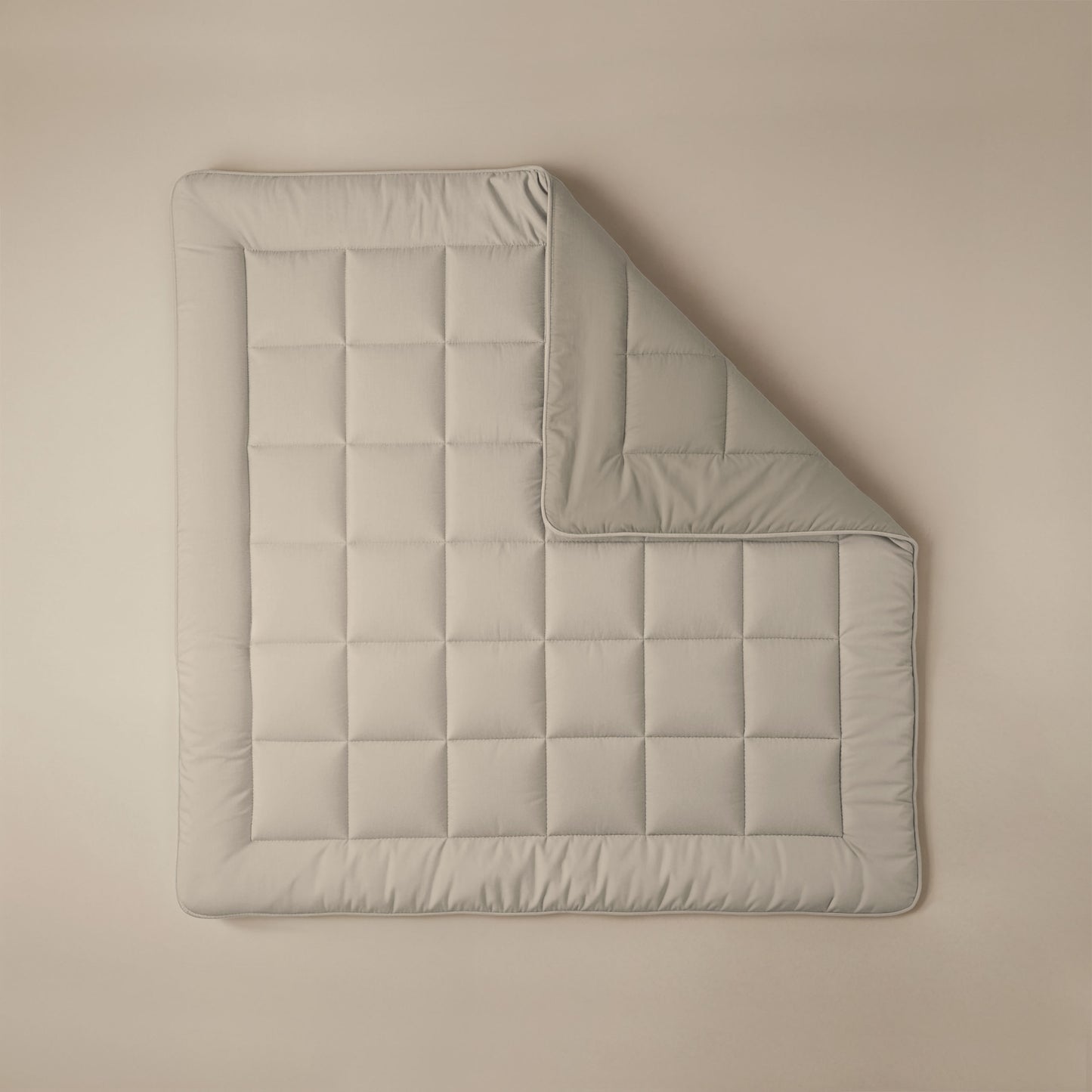 Het Zelesta Comfort Duo Dekbed in taupe & champagne, netjes gewatteerd met een omgeslagen hoek, staat op een beige achtergrond - perfect voor wie klassieke dekbedden en comfort het hele jaar door belangrijk vindt.