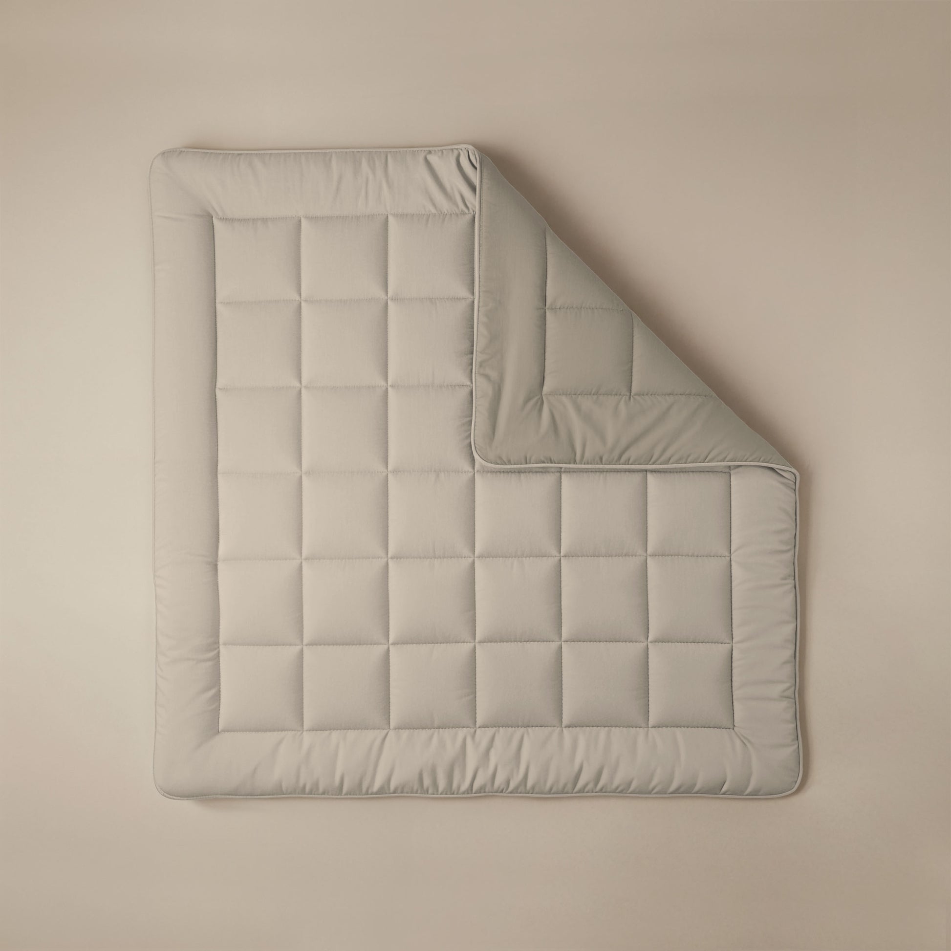 Het Zelesta Comfort Duo Dekbed in taupe & champagne, netjes gewatteerd met een omgeslagen hoek, staat op een beige achtergrond - perfect voor wie klassieke dekbedden en comfort het hele jaar door belangrijk vindt.