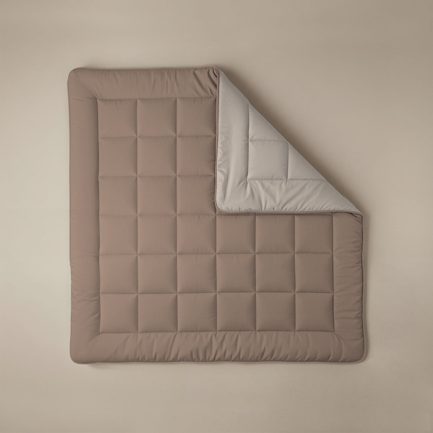 Het Zelesta Comfort Duo Dekbed - Terra & Zand is een bruine gewatteerde deken met een rasterpatroon, geïnspireerd op klassieke dekbedden. De deken is gedeeltelijk opgevouwen zodat de lichtgrijze onderkant zichtbaar wordt, en plat neergelegd voor een look het hele seizoen door.