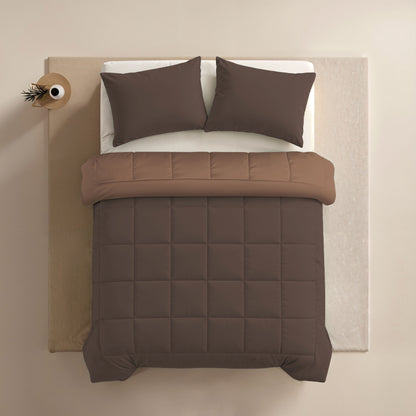 Een netjes opgemaakt bed met het Zelesta Comfort Duo Dekbed in chocolade bruin & mokka, twee bruine kussens en een kleine ronde vaas met een tak aan de linkerkant, allemaal gerangschikt op een lichtgekleurde ondergrond.