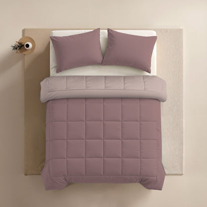 Netjes opgemaakt bed met mauve dekbed, twee kussens met Zelesta Comfort Duo Kussensloop - Oudroze (60x70cm), en een lichtgrijs bovenlaken, van bovenaf gezien. Een klein rond bijzettafeltje met een vaas staat naast het bed.
