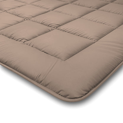 Een close-up van het Zelesta Comfort Duo Dekbed in Terra & Zand, een lichtbruin gewatteerde matrastopper voor alle seizoenen met vierkant gestikte delen en afgeronde hoeken.