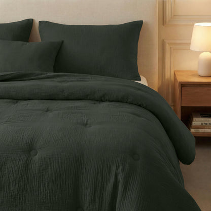 Een netjes opgemaakt bed met de Zelesta Japandibed Katoen Mousseline in groen, bijpassende kussens, een beige gestoffeerd hoofdeinde, een houten nachtkastje en een brandende tafellamp.