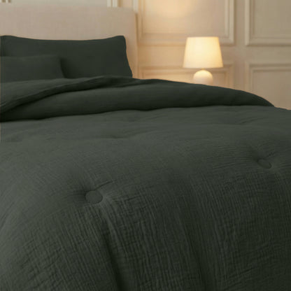 Een keurig opgemaakt bed met de Zelesta Japandibed Katoen Mousseline - Groen en kussens staat naast een brandend bedlampje, tegen een crèmekleurige muur met paneeldetails.