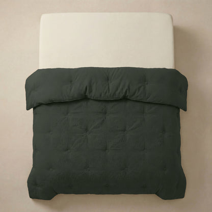 Een netjes opgemaakt bed met een crèmekleurig matras en het Zelesta Japandibed Katoen Mousseline - Green, een donkergroen getuft dekbed van dubbelgeweven katoen, van bovenaf gezien tegen een neutrale achtergrond.