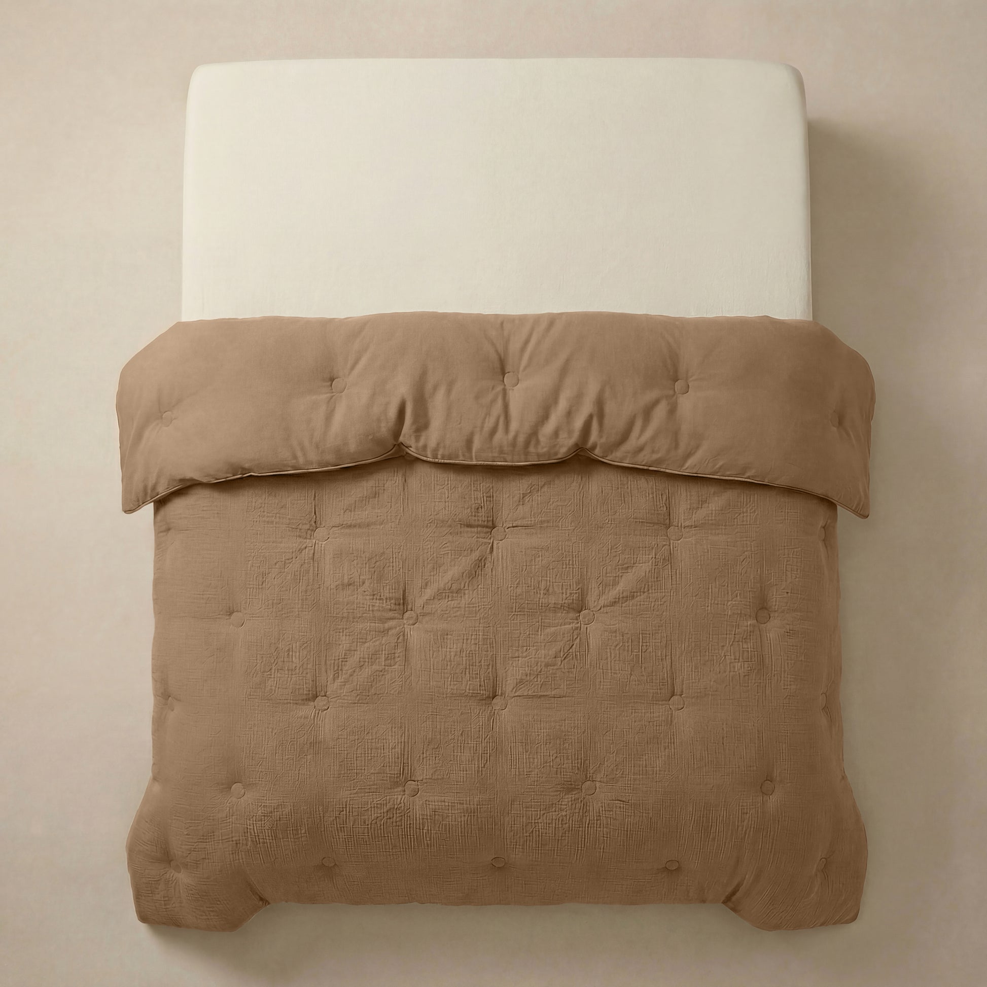 Het Zelesta Japandibed Katoen Mousseline - Bruin is een beige gestoffeerd bed met een crèmekleurige matras, met daarop een lichtbruin, getuft dekbed van zacht mousseline katoen en netjes gerangschikt.