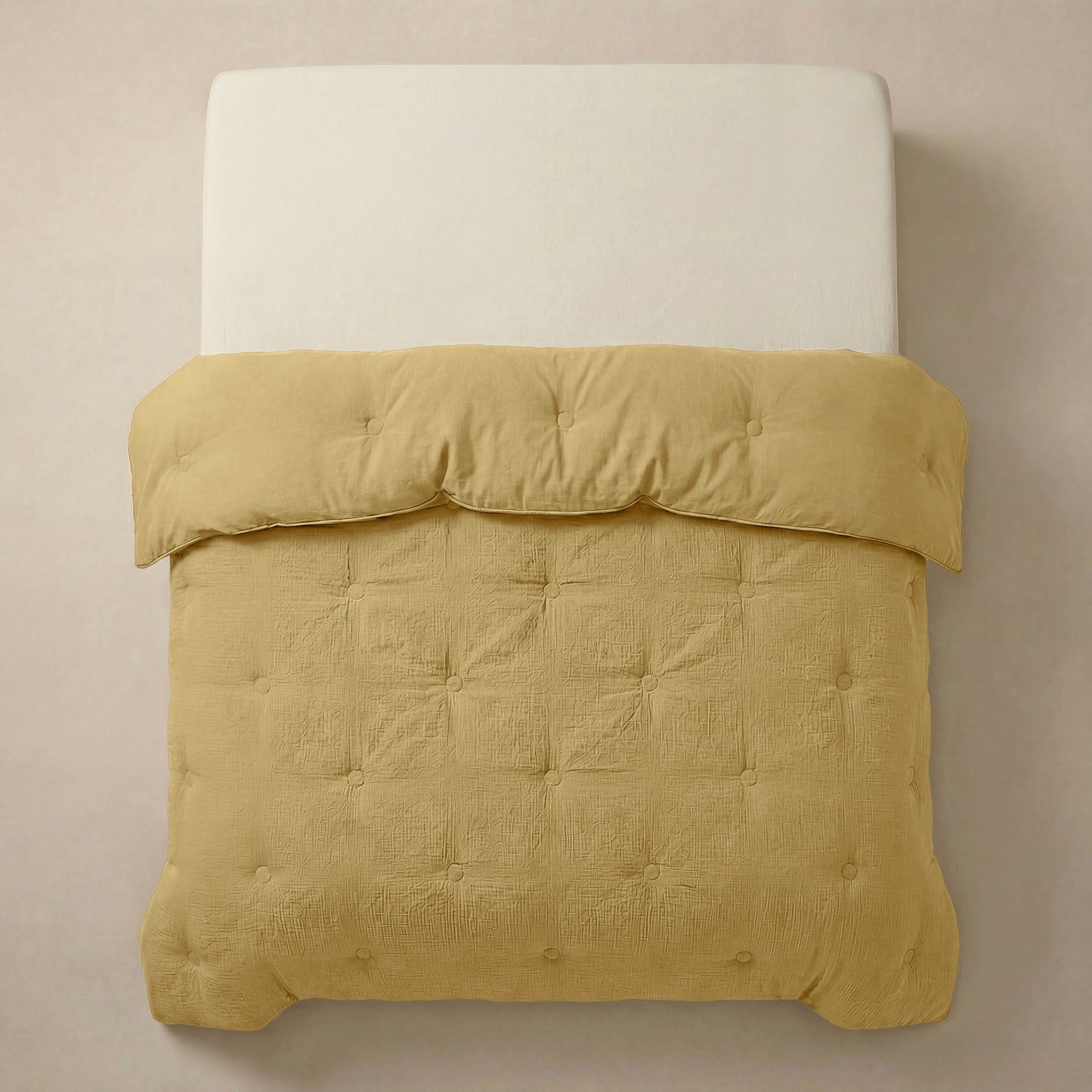 Het Zelesta Japandibed Katoen Mousseline - Oker heeft een witte matras en een getuft, goudgeel Japandi dekbed van zachte katoenmousseline, van bovenaf gezien tegen een neutrale achtergrond.
