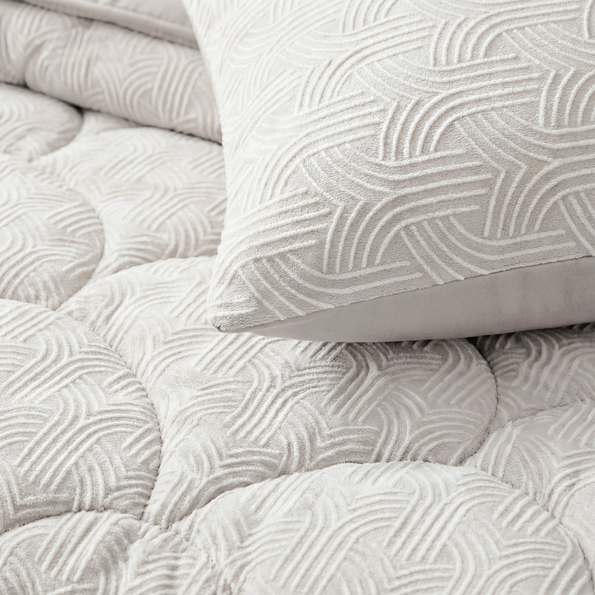 Close-up van Zelesta Flanel Luxe - Crèmekussen en doorgestikt beddengoed met een verhoogd geometrisch patroon in lichtbeige, dat het ultrazachte comfort biedt van een microvezel dekbed.