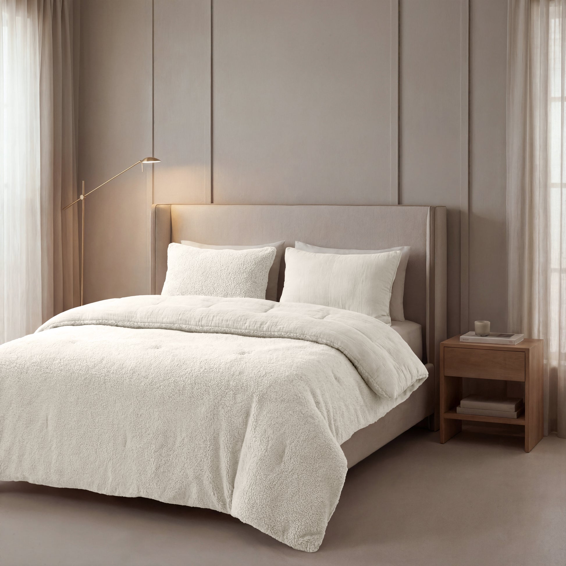 Een netjes opgemaakt bed met Zelesta Teddy Katoen Mousseline - Beige beddengoed staat tegen een beige wand, naast een houten nachtkastje en staande lamp, in een zacht verlichte slaapkamer.