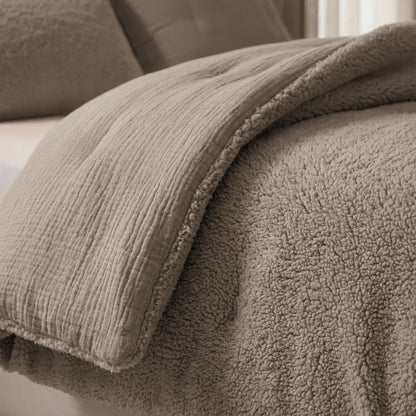 Close-up van een netjes opgemaakt bed met het Zelesta Teddy Katoen Mousseline - Taupe dekbed, met taupekleurige stof en een zachte sherpa voering, plus bijpassend kussen.