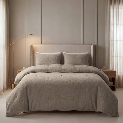 Een netjes opgemaakt bed met Zelesta Teddy Katoen Mousseline - Taupe beddengoed, twee kussens en een getuft hoofdeinde wordt geflankeerd door houten nachtkastjes en een gouden staande lamp in een zacht verlichte slaapkamer.