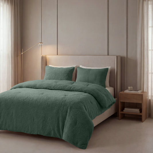 Een netjes opgemaakt bed met het Zelesta Teddy Katoen Mousseline - Groen dekbed en kussens, in een minimale slaapkamer met beige muren, een houten nachtkastje en een staande lamp.