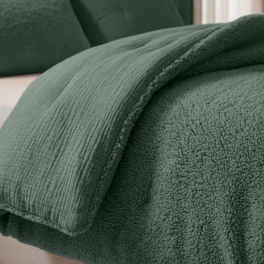 Close-up van een netjes opgemaakt bed met de Zelesta Teddy Katoen Mousseline - Groen, met een gestructureerd, temperatuurregulerend dekbed met pluche sherpa onderkant en bijpassende kussenslopen.