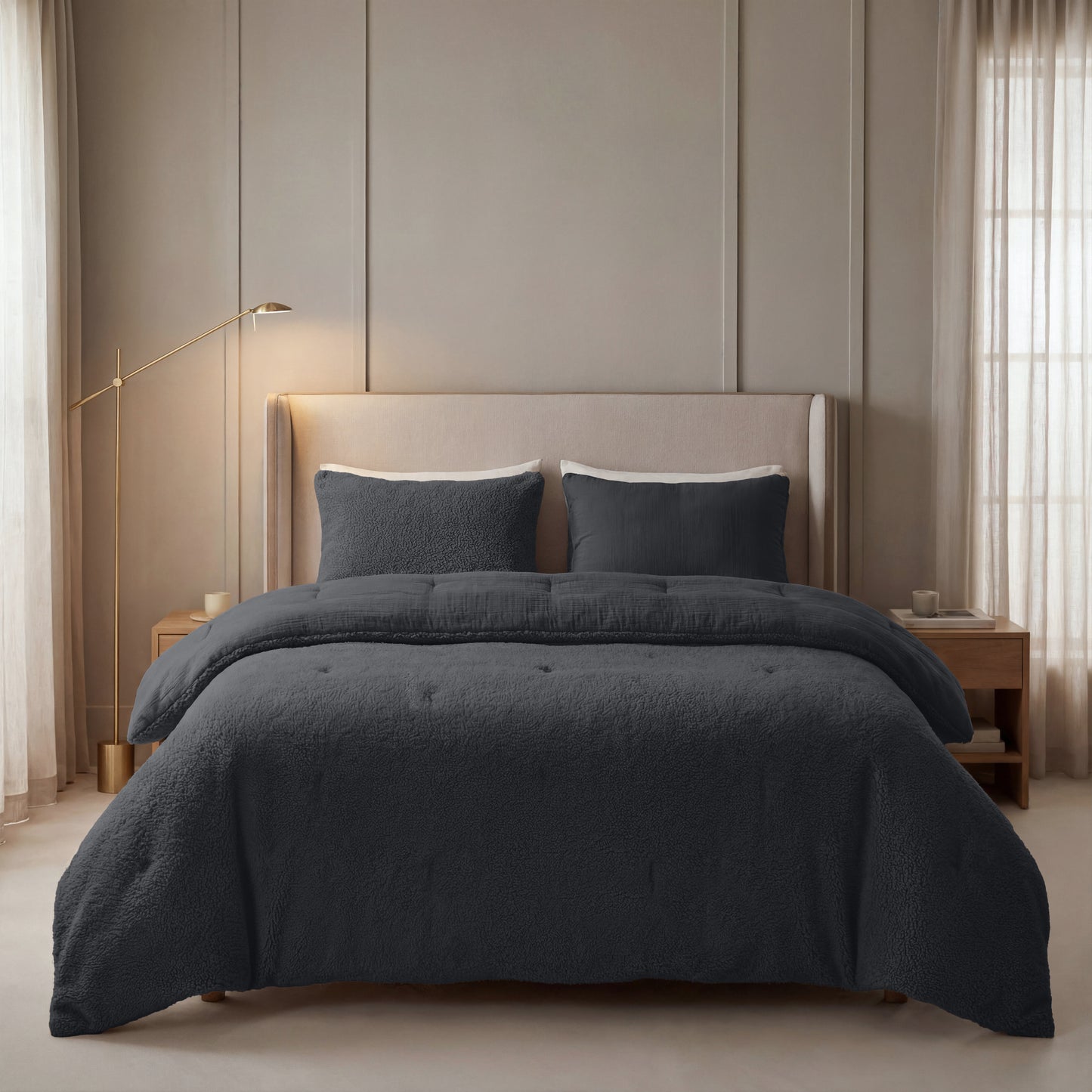 Een netjes opgemaakt bed met Zelesta Teddy Katoen Mousseline beddengoed in antraciet, twee bijpassende kussens, een beige gestoffeerd hoofdeinde en houten nachtkastjes in een zacht verlichte, neutrale slaapkamer.