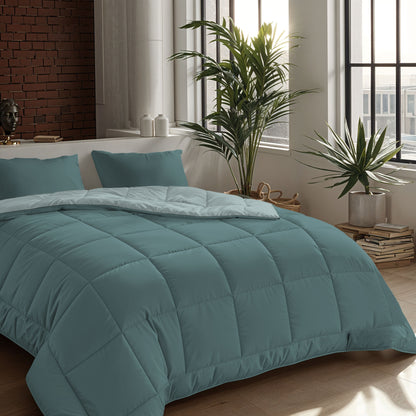 Een keurig opgemaakt bed met een groenblauw dekbed en twee Zelesta Comfort Duo Kussensloop - Mineraal kussens (60x70cm) in een moderne slaapkamer met grote ramen, potplanten en gestapelde boeken op de vloer.