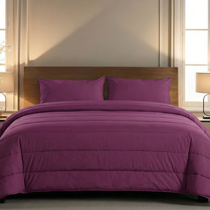 Een keurig opgemaakt bed met een houten hoofdeinde, pruimkleurig beddengoed en bijpassende kussens kenmerkt het Zelesta Comfort Uni Dekbed in Bordeaux, geflankeerd door twee nachtkastjes met lampen.