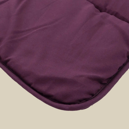 Close-up van een gevoerde, kastanjebruine stoffen hoek met gestikte randen van het Zelesta Comfort Uni Dekbed - Bordeaux, tegen een effen beige achtergrond.