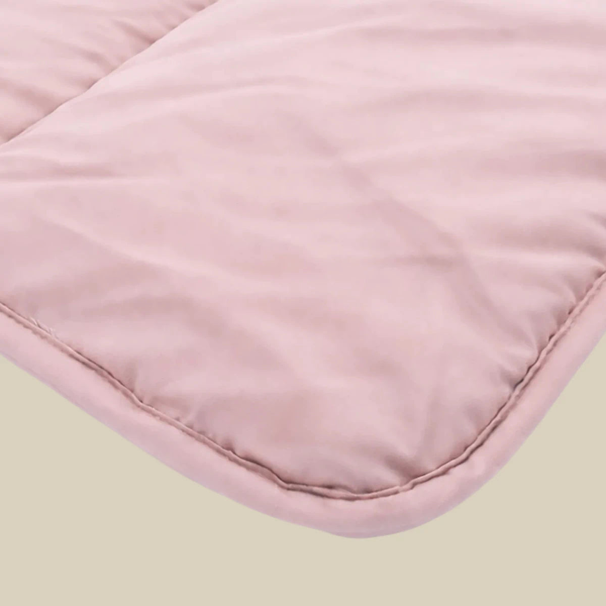 Close-up van het Zelesta Comfort Uni Dekbed - Oud Roze toont lichtroze gewatteerde stof met zichtbare stiksels, ideaal voor een klassiek dekbed of all season dekbed, dat comfort en tijdloze stijl biedt.