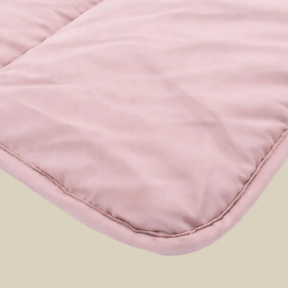 Close-up van het Zelesta Comfort Uni Dekbed - Oud Roze toont lichtroze gewatteerde stof met zichtbare stiksels, ideaal voor een klassiek dekbed of all season dekbed, dat comfort en tijdloze stijl biedt.