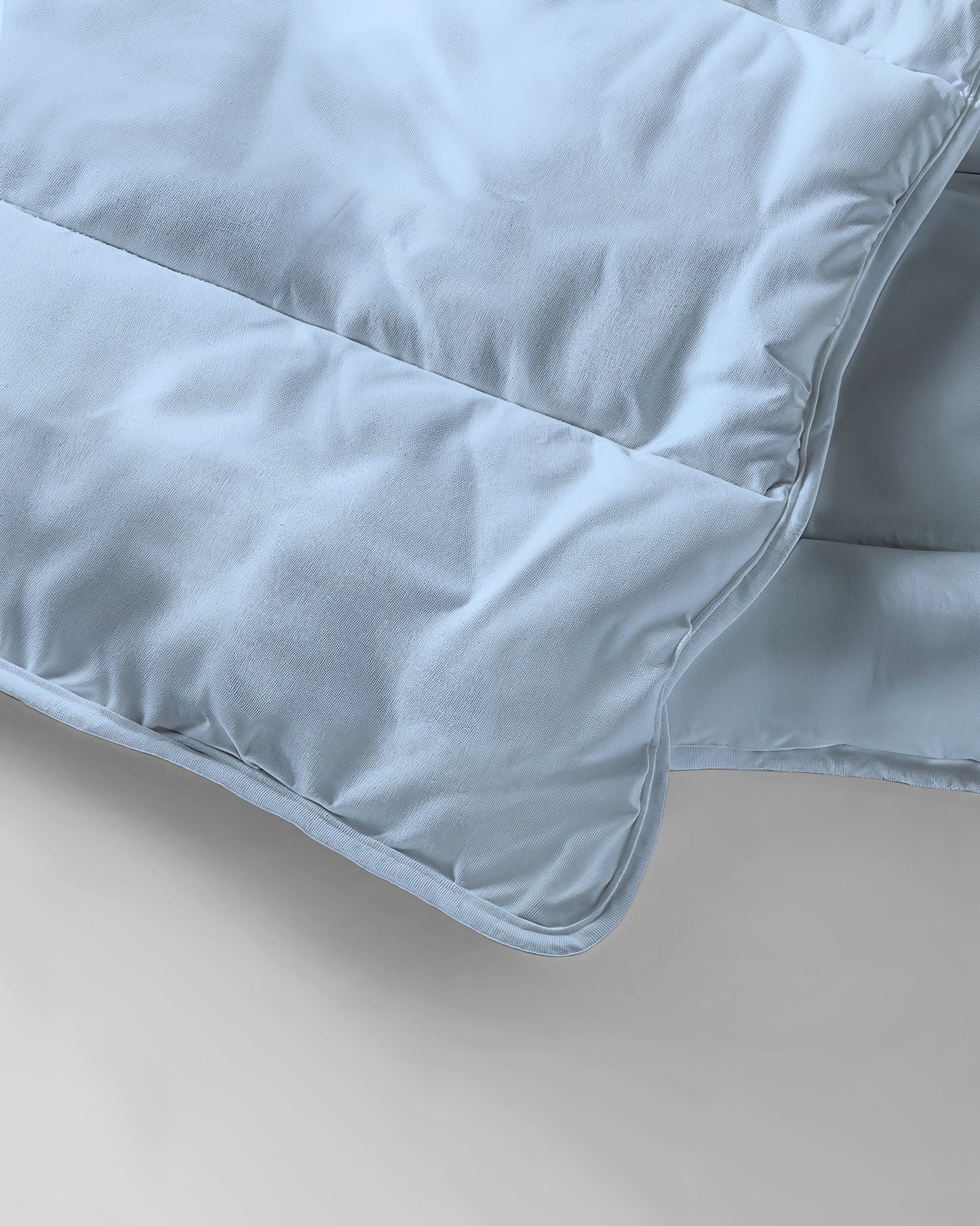Een close-up van het Zelesta Everyday Uni Dekbed - Lichtblauw, met zijn zachte stof en gedetailleerde stiksels - ideaal als dekbed en overtrek in één voor comfort het hele seizoen door.