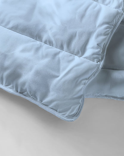 Een close-up van het Zelesta Everyday Uni Dekbed - Lichtblauw, met zijn zachte stof en gedetailleerde stiksels - ideaal als dekbed en overtrek in één voor comfort het hele seizoen door.