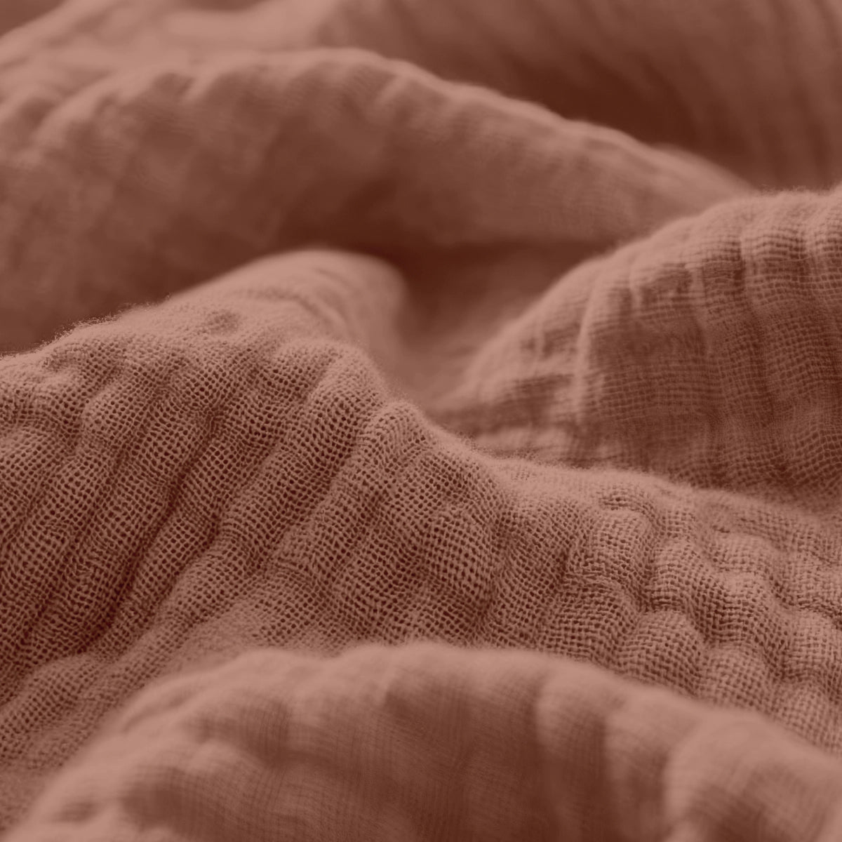 Close-up van verfrommeld, gestructureerd Mousseline Hoeslaken - Dusty-Rose stof met zichtbare geweven vezels en zachte plooien - ideaal voor ademend beddengoed of een stijlvol Japandi lakentje.