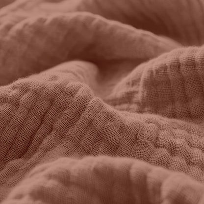 Close-up van verfrommeld, gestructureerd Mousseline Hoeslaken - Dusty-Rose stof met zichtbare geweven vezels en zachte plooien - ideaal voor ademend beddengoed of een stijlvol Japandi lakentje.