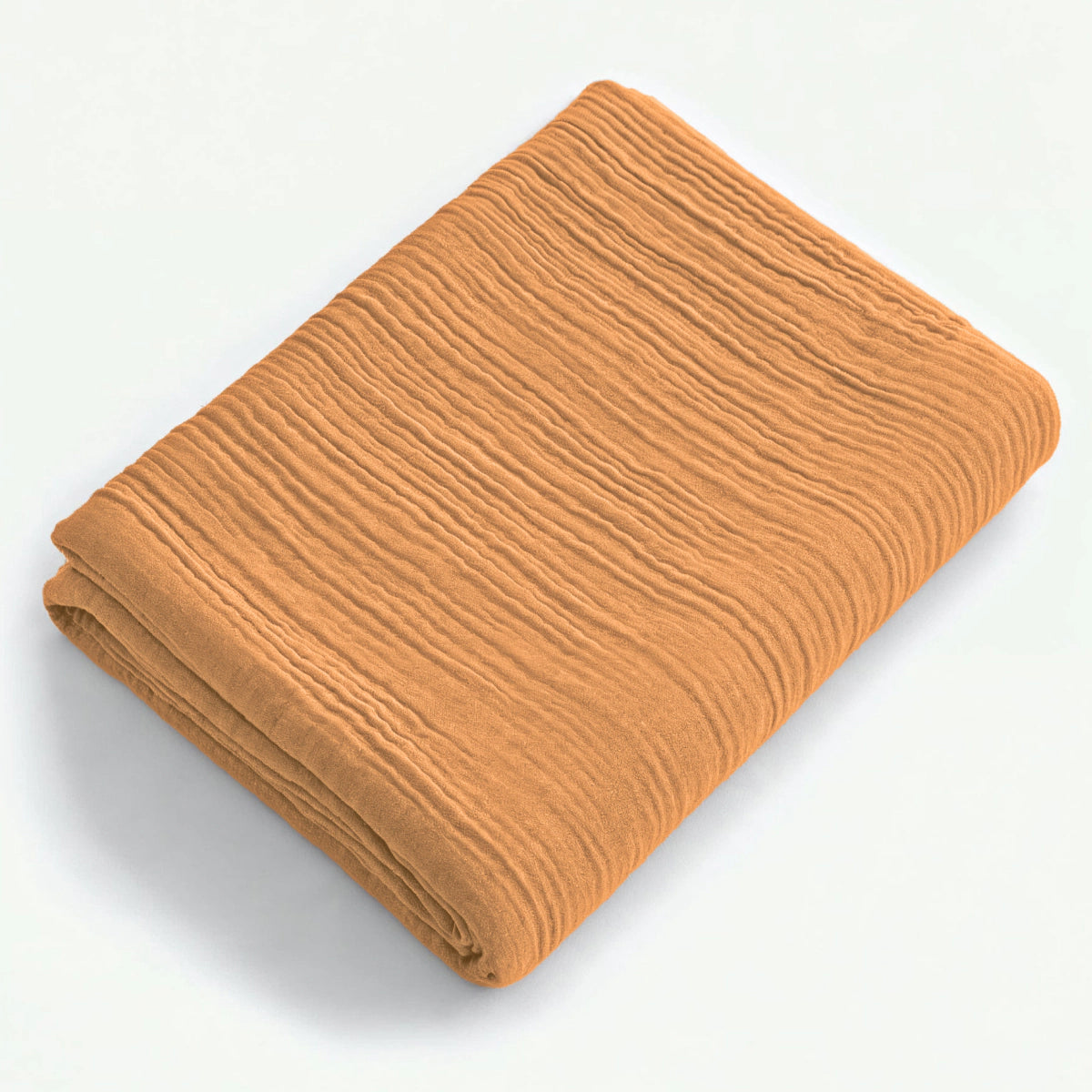 Een gevouwen, gestructureerde Mousseline Hoeslaken - Terra in lichtbruin wordt weergegeven op een effen wit oppervlak.