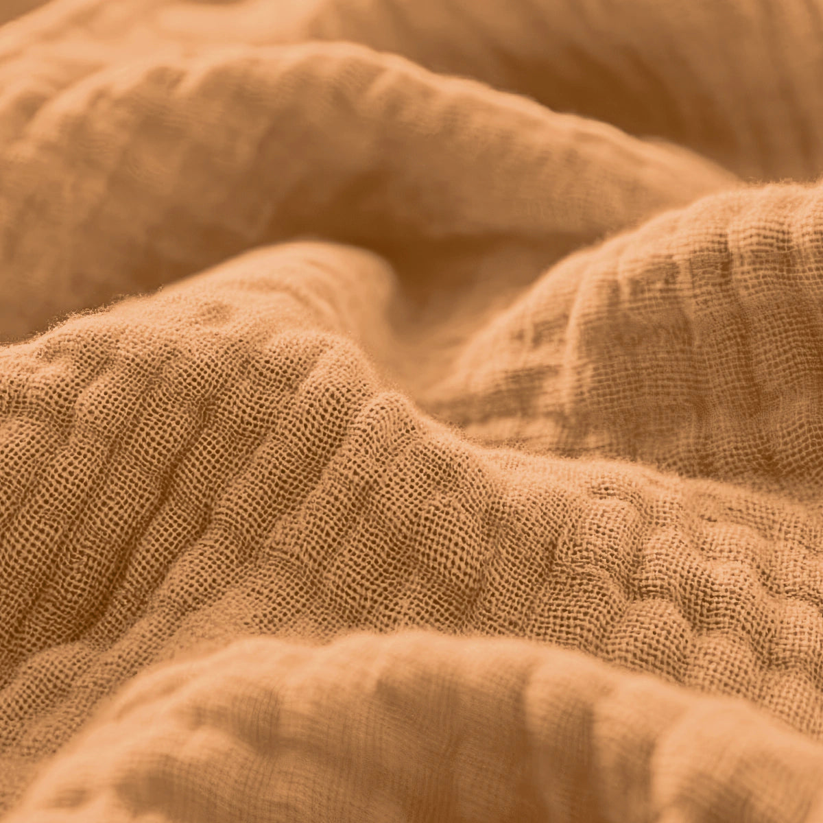 Close-up van Mousseline Hoeslaken - Terra, een getextureerde lichtbruine katoenstof met zichtbare weefdraden en zachte plooien, ideaal voor ademend beddengoed in Japanse stijl.