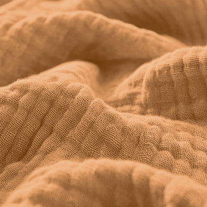 Close-up van Mousseline Hoeslaken - Terra, een getextureerde lichtbruine katoenstof met zichtbare weefdraden en zachte plooien, ideaal voor ademend beddengoed in Japanse stijl.