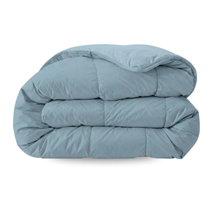 Het Zelesta Pure Uni Dekbed in sereen blauw, netjes gevouwen op een witte ondergrond, biedt ademend slaapcomfort voor een rustige nacht.