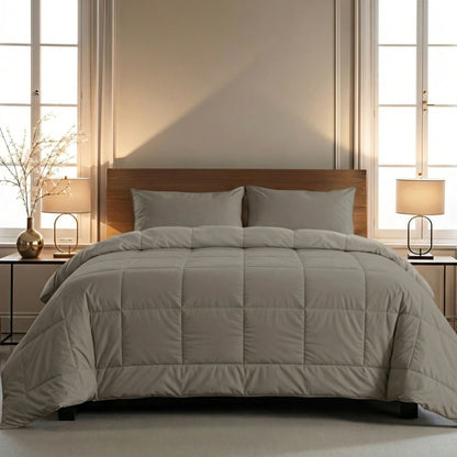 Een keurig opgemaakt bed met het Zelesta Pure Uni Dekbed - Antraciet Grijs en kussens, geflankeerd door twee nachtkastjes met bijpassende lampen, tegen grote ramen in een zacht verlichte slaapkamer voor ademend slaapcomfort.