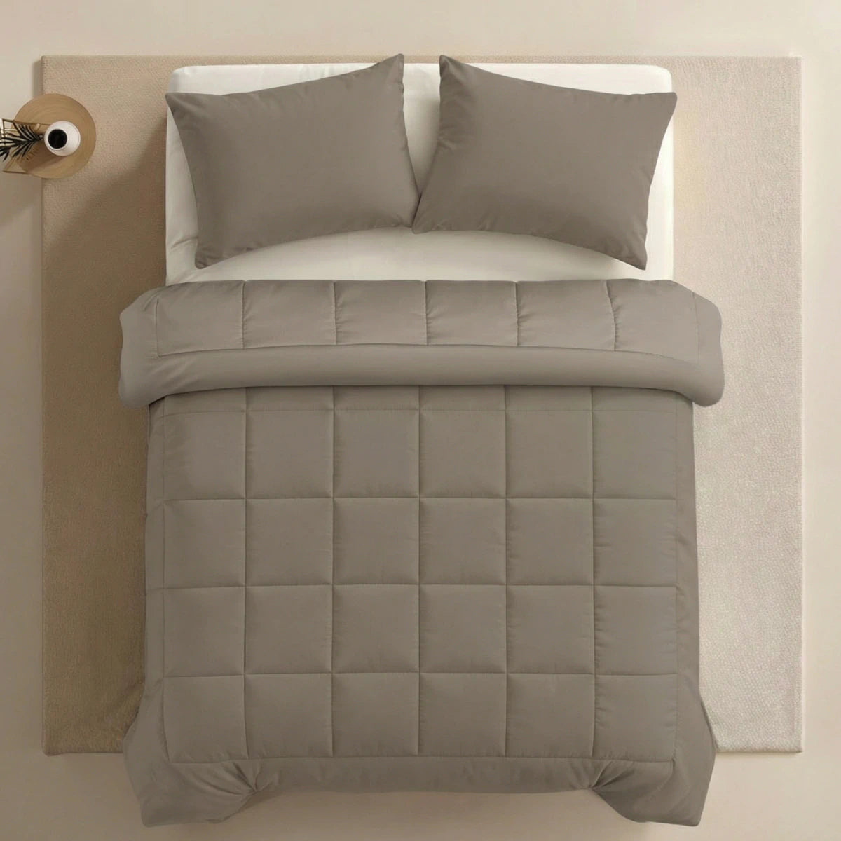 Bovenaanzicht van een netjes opgemaakt bed met het Zelesta Pure Uni Dekbed in antraciet grijs en twee bijpassende kussens op een wit laken, geplaatst op een lichtgekleurd vloerkleed voor optimaal slaapcomfort.